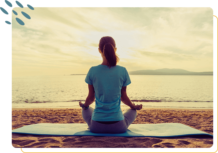 A woman sitting on the beach doing yoga.