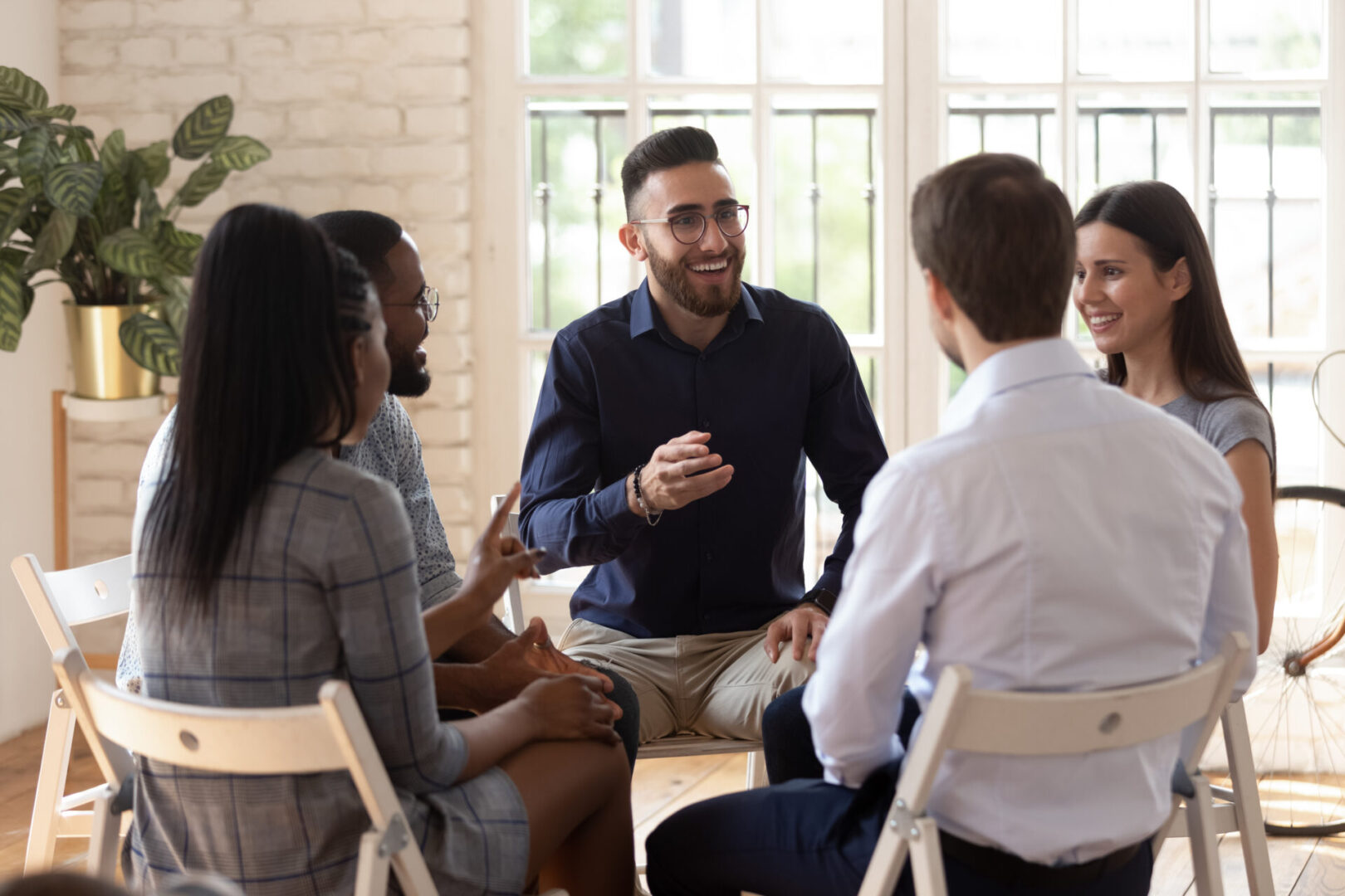 Positive people sit in circle take part in team building or therapy session, try to solve problems or do training exercise, focus on arabian man telling story share experience at group meeting concept